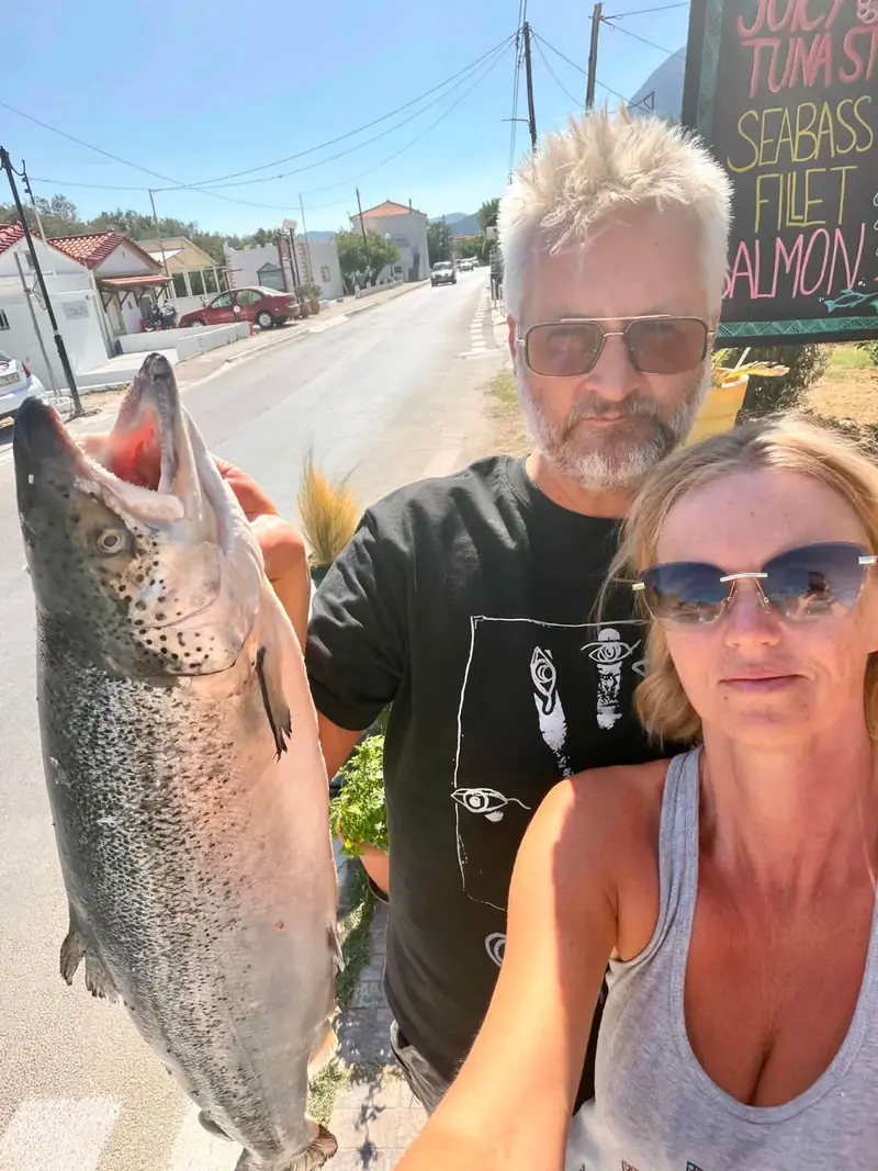 The owners outside the restaurant holding a fresh salmon